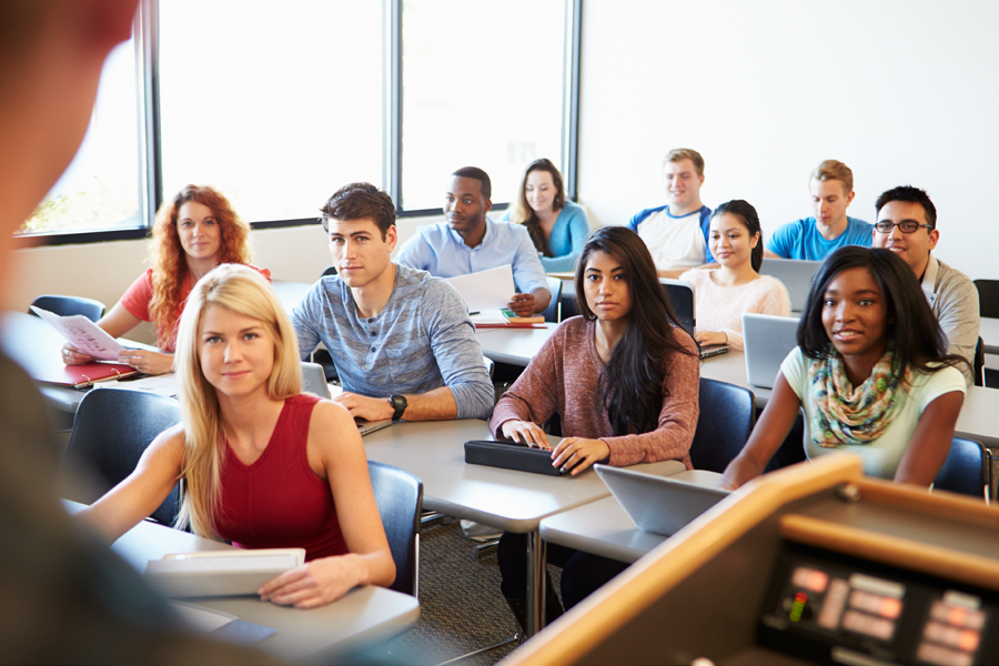 Professor goes over a syllabus to a group of college students who are actively paying attention.